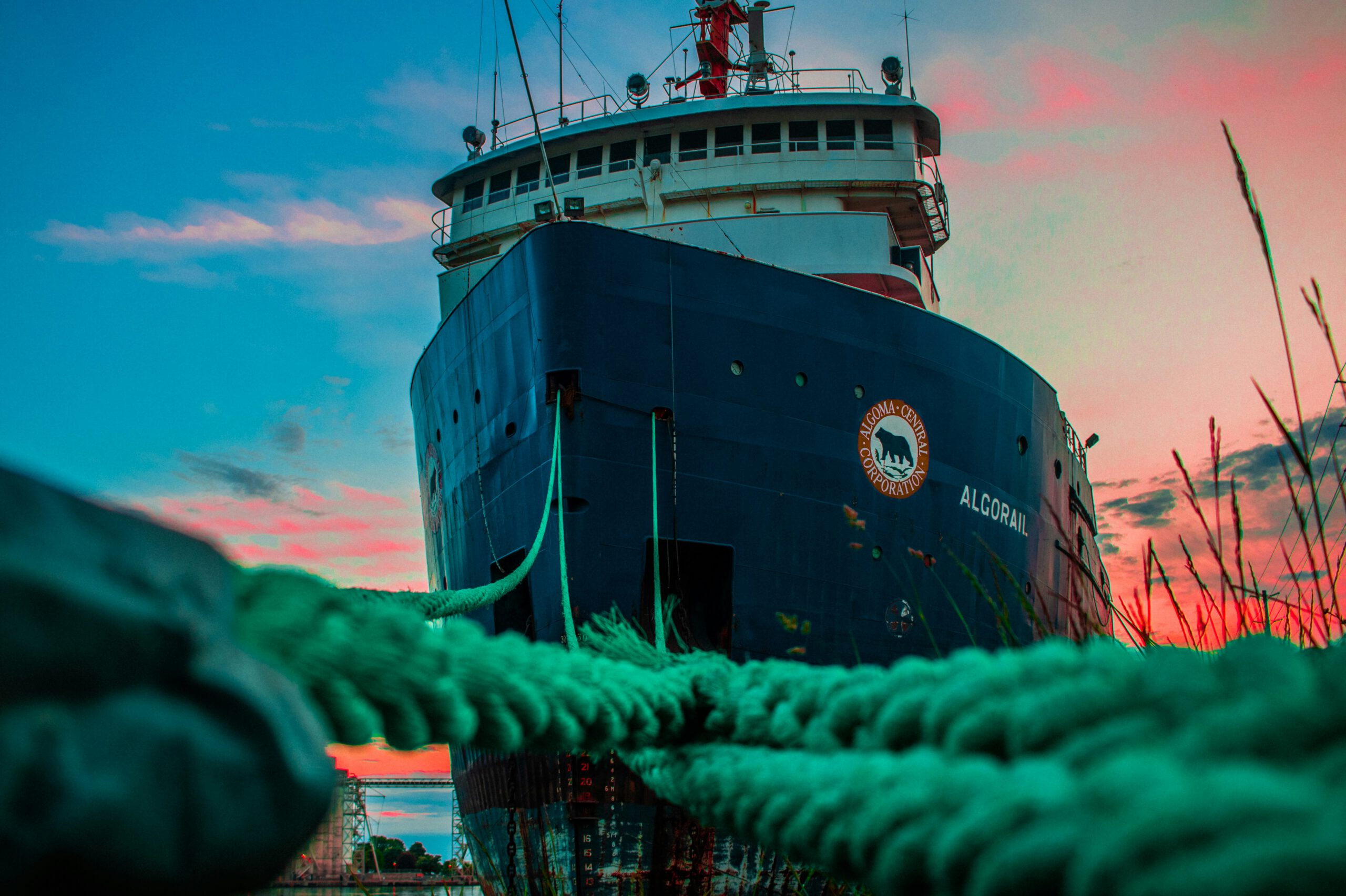 commercial shipping vessel docked, sun setting in the sky